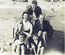 O'Neil poses on the sandy beach with a British family of four, seated