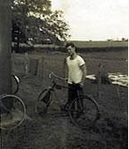 Sgt. O’Neil wearing a white t-shirt, stands next to a bicycle